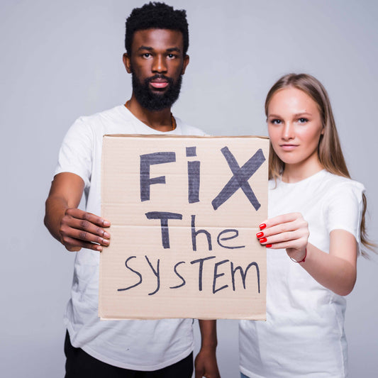 A Black man and white woman holding a sign that says, "Fix the System," a nod to the Ally League's mission to unite against racism